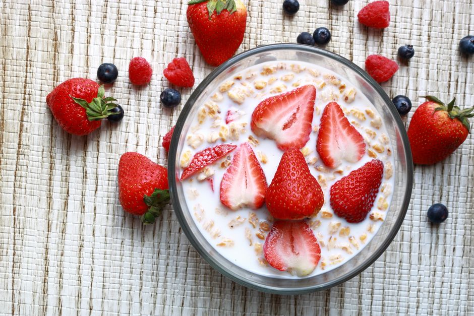 Bowl of cereal and milk topped with strawberries and blueberries