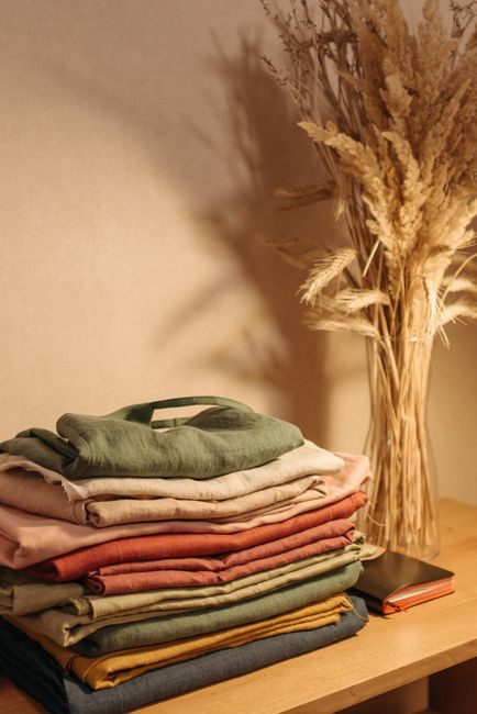 Folded garments in earthy colours on a wooden table